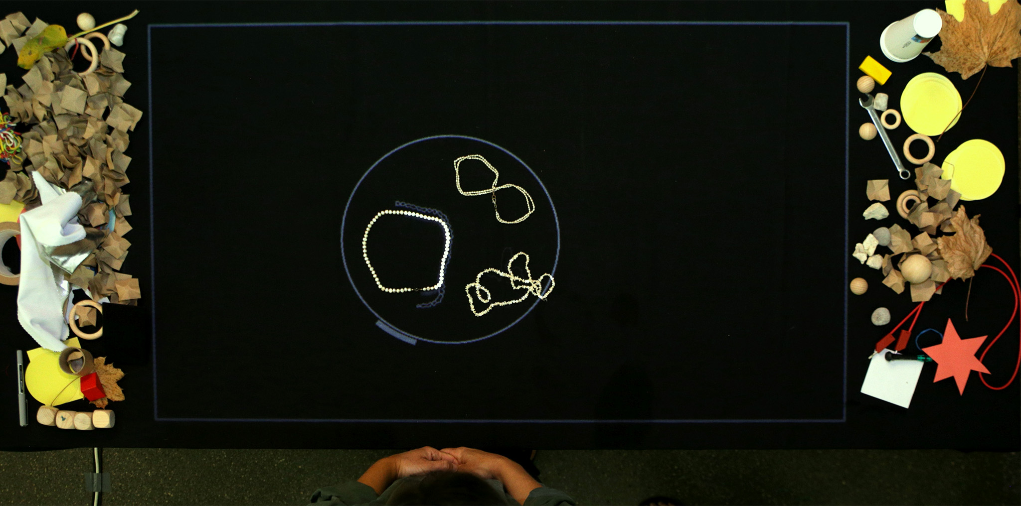 A pearl necklace, a handbag and a chain on the table, traced by light