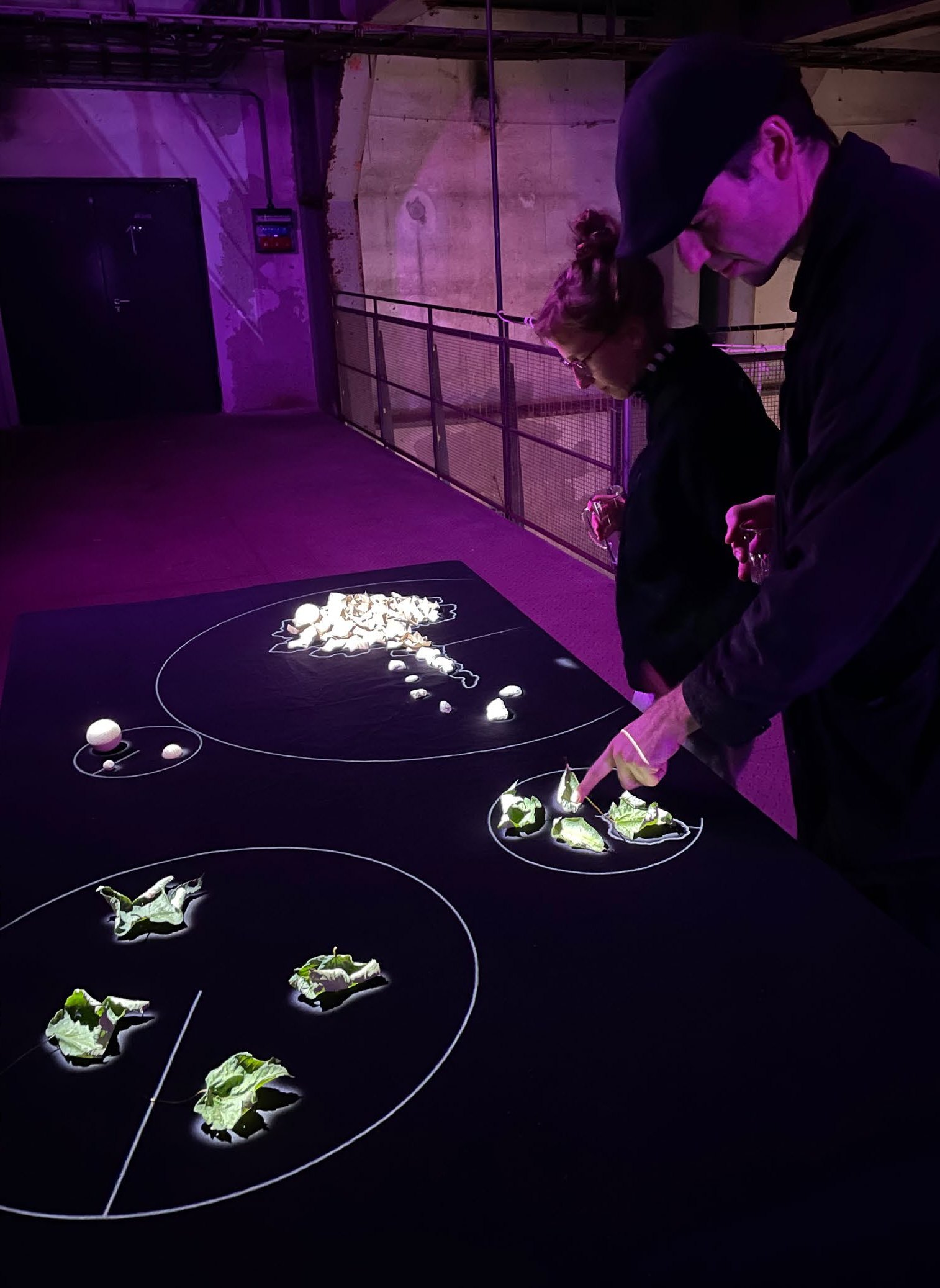 Two visitors placing leaves on the table at Schmiede 2024